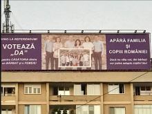  Imaginea prezintă un copil încadrat de două “mame” în loc de un tată și o mamă. Postarea încurajează cetățenii să apere familia și să voteze da la referendum.